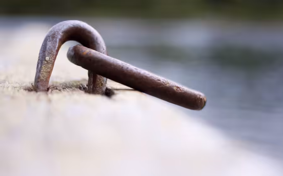 Verrosteter Metallring auf Holzoberfläche am Wasser