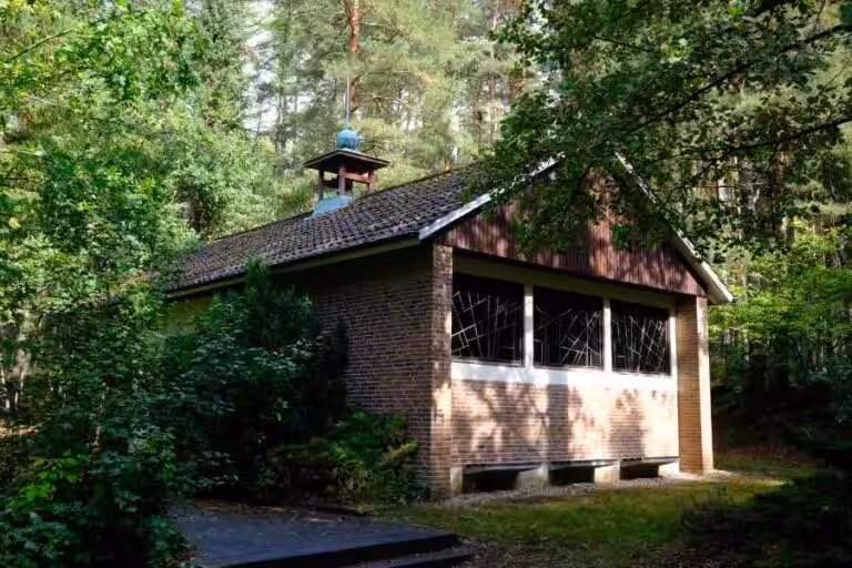 Ziegelgebäude im Wald mit Glockenturm.