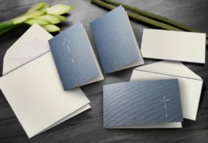 Einladungskarten mit Kreuz und Umschläge auf Tisch.