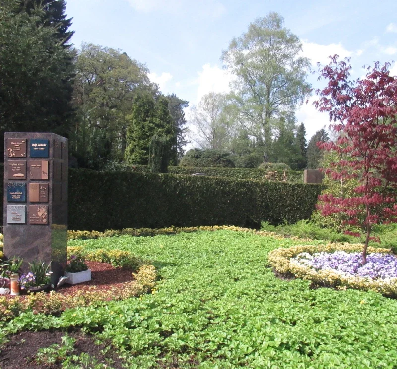 Blumenbeet mit Gedenkstein im Friedhof