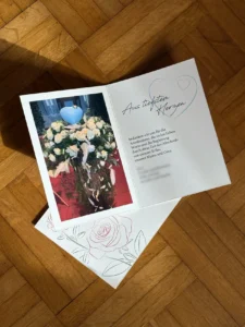 Trauer-Dankeskarte mit Urne und weißen Blumen auf Parkett