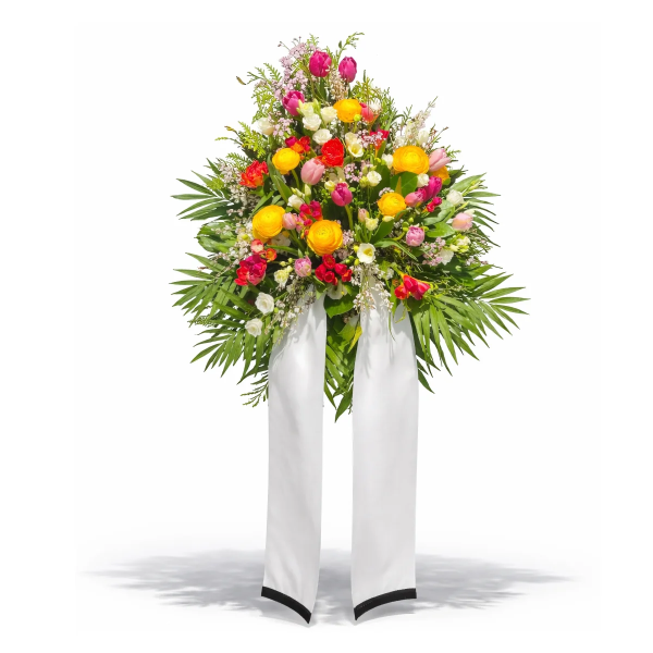 Buntes Blumengesteck auf weißem Ständer mit Tulpen und Ranunkeln