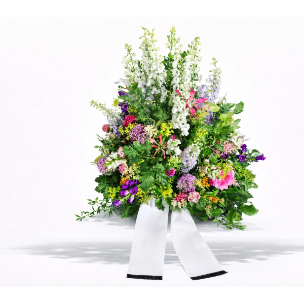 Trauergesteck mit bunten Blumen und weißer Schleife