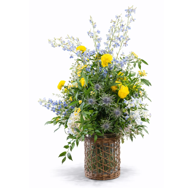 Sommerlicher Blumenstrauß in Weidenkorb mit blauen und gelben Blüten